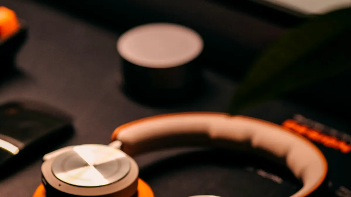 A pair of over-ear headphones resting on a desk under warm light.