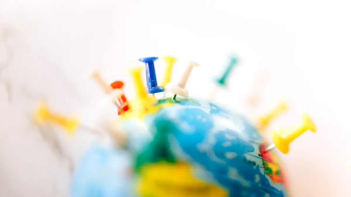 A globe marked with coloured push pins in several countries.