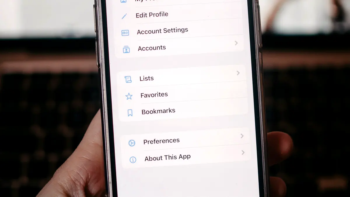 A hand holding a phone open at the settings menu.