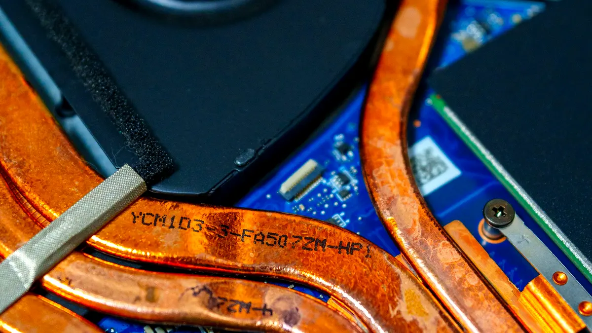 The inside of a laptop's cooling assembly: flattened copper heat pipes running from the chip to a small radiator beside the fan.