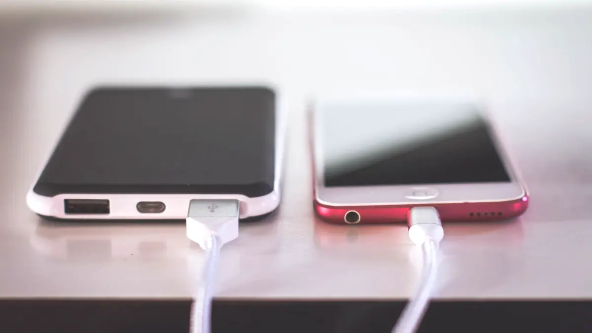 Two smartphones charging side by side on a desk.