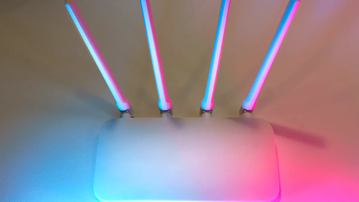 A wireless router with four antennas, lit in blue and pink.