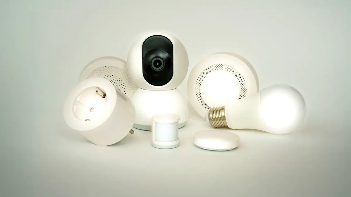An assortment of smart home devices — bulbs, sockets and a camera — on a plain background.