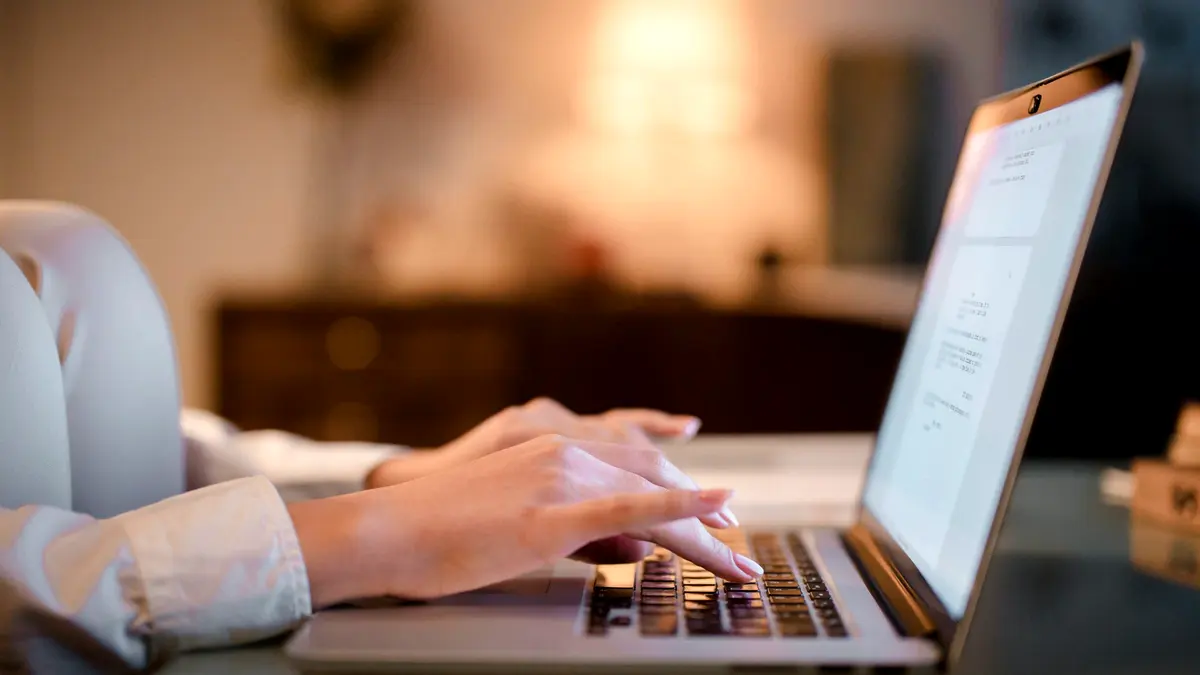 Close-up of hands typing on a laptop keyboard.